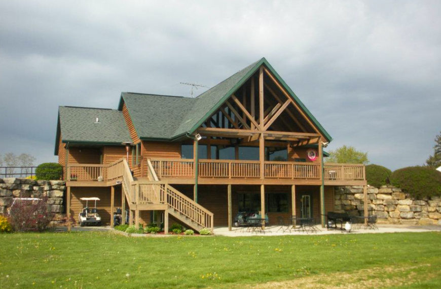 aaExterior image of Creekview Par THree, a large log cabin building overlooking a golf course