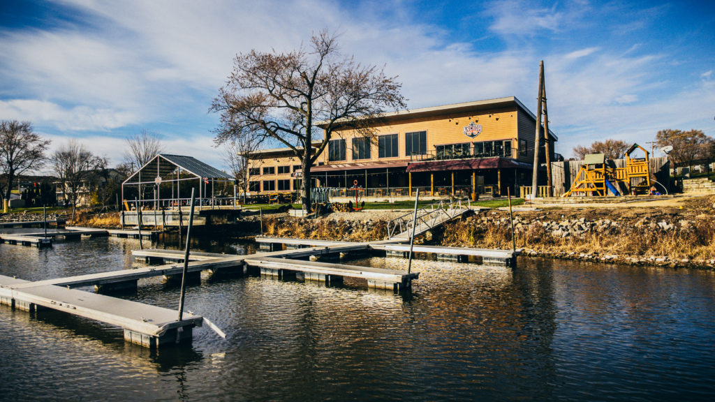 The backside of Anchor, a large brown building with a boating dock alongthe Rock River