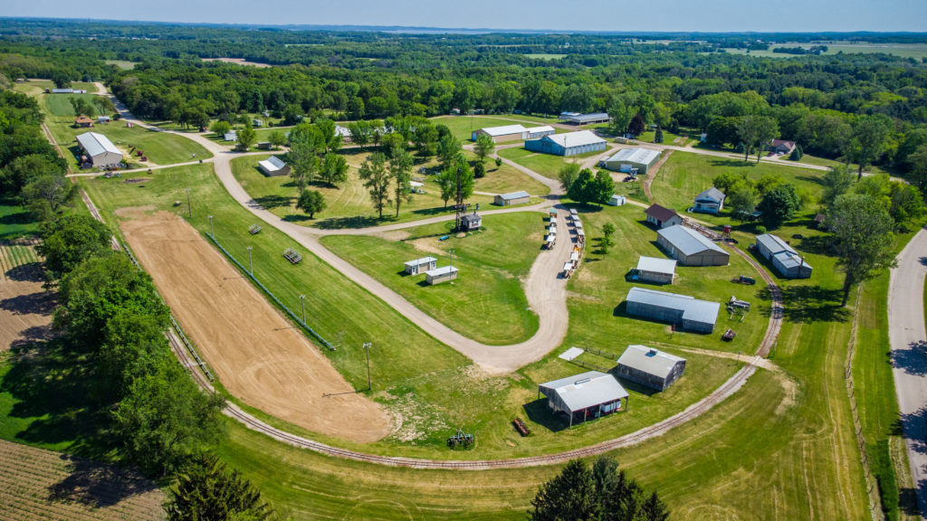 Aerial view of a large park with bright green grass and several buildings and pavilions for groups to host events