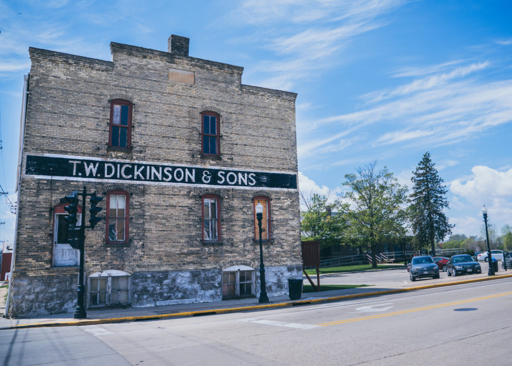 A tall bric building with a sign that says TW Dickinson on the side above the door