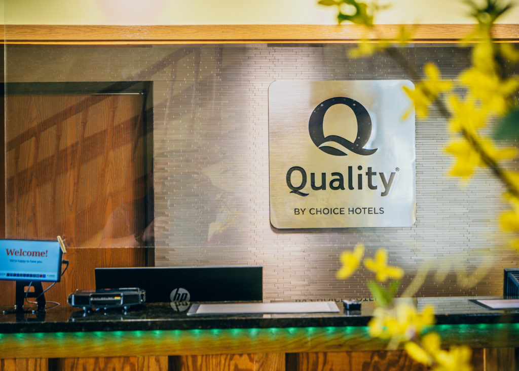 A photo of the check in desk at Quality Inn with a sign featuring the company logo.